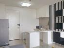 Modern kitchen with white cabinets, striped accent wall, and small dining area