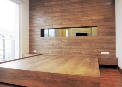 Modern wooden bedroom with a platform bed and large window