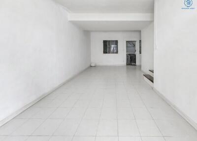 Spacious empty living room with white walls and tiled flooring