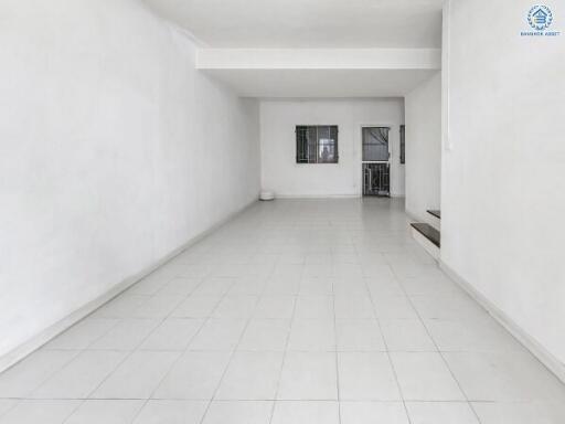 Spacious empty living room with white walls and tiled flooring