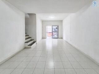 Spacious living room with tiled floors and staircase leading to upper level