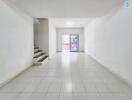 Spacious living room with tiled floors and staircase leading to upper level