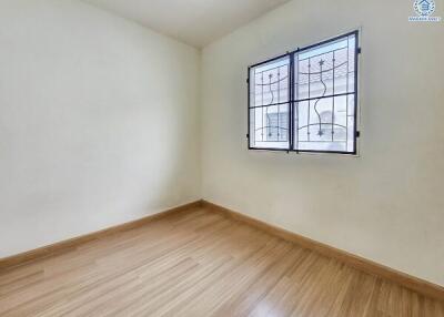 Empty bedroom with wooden flooring and window with metal bars