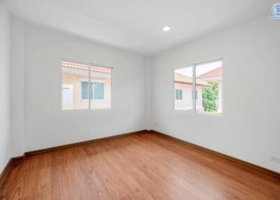 Bright empty bedroom with hardwood flooring and large windows