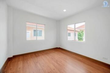 Bright empty bedroom with hardwood flooring and large windows