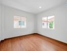 Bright empty bedroom with hardwood flooring and large windows