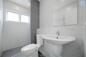 Modern bathroom with a toilet, sink, and large mirror.