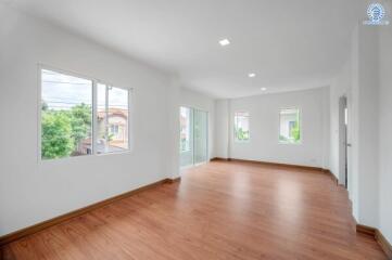 Bright and spacious living room with wooden flooring and large windows