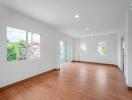 Bright and spacious living room with wooden flooring and large windows