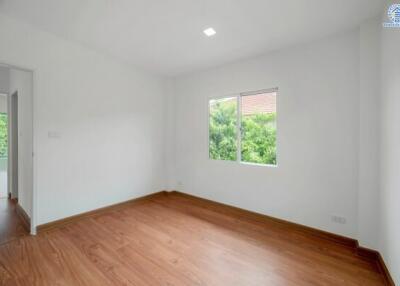 Empty bedroom with hardwood floors and a window with garden view