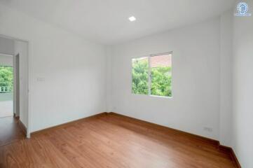 Empty bedroom with hardwood floors and a window with garden view