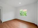 Empty bedroom with hardwood floors and a window with garden view