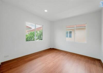 Empty bedroom with hardwood floors and windows with exterior view
