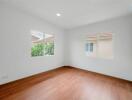 Empty bedroom with hardwood floors and windows with exterior view