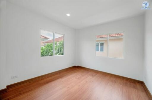 Empty bedroom with hardwood floors and windows with exterior view