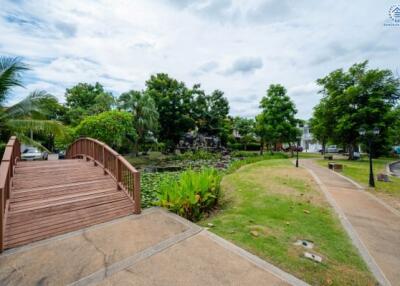 Community garden area with wooden bridge, pond, and walking paths