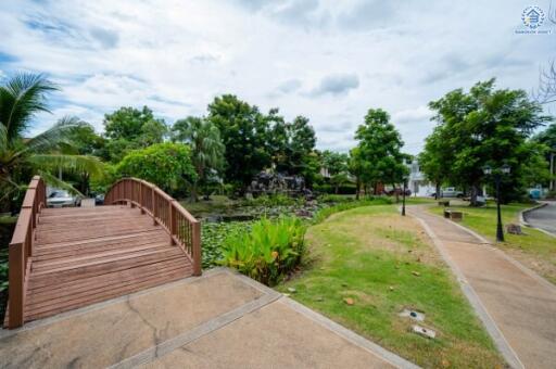 Community garden area with wooden bridge, pond, and walking paths