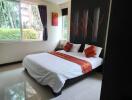 Modern bedroom with large window and bed with orange accents