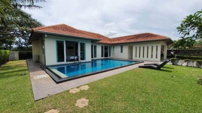 Image of a modern house with a swimming pool and a lawn area.