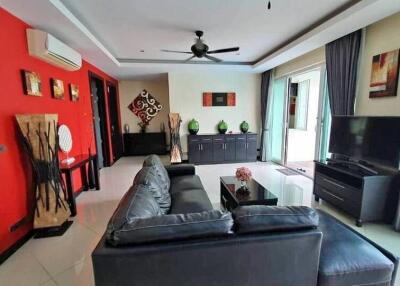 Modern living room with a black sofa, wall art, and large windows