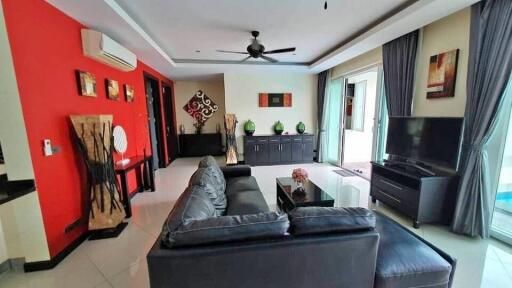 Modern living room with a black sofa, wall art, and large windows