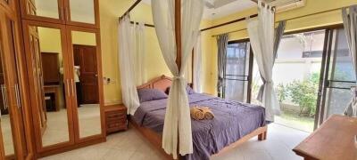 Spacious bedroom with four-poster bed and large windows.