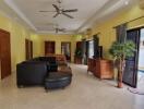 Spacious living room with black sofas, ceiling fans, and pool view