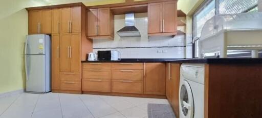 Modern kitchen with wooden cabinets, appliances, and large windows