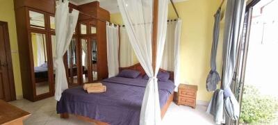 Bedroom with large wooden framed bed, mirrors, windows and curtains