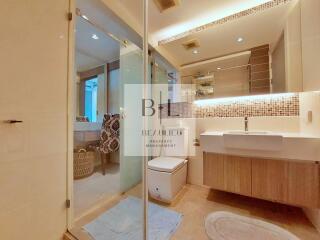 Modern bathroom with glass shower, wooden vanity, and large mirror