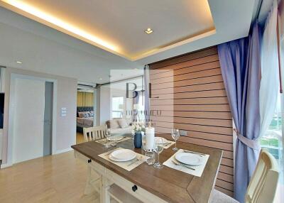 Modern dining area with table set for two, adjacent to living space