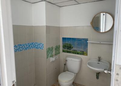 A bathroom with tiled walls, a toilet, sink, and a mirror.