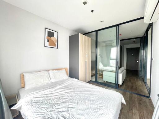 A modern bedroom with a bed, large wardrobe, and glass partition leading to a seating area