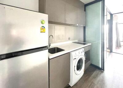 Modern kitchen with integrated white goods including a refrigerator, washing machine, and induction hob.