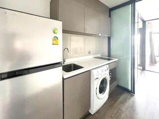 Modern kitchen with integrated white goods including a refrigerator, washing machine, and induction hob.