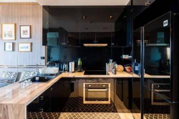 Modern kitchen with black cabinetry, marble countertops, and stainless steel appliances