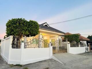 Exterior view of a modern house with a gated entrance and landscaped trees