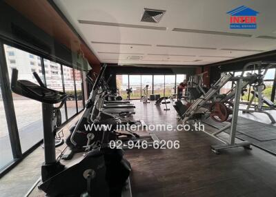 Indoor gym with various exercise equipment and large windows