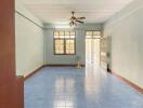 Spacious empty living area with ceiling fan and blue tiled floor