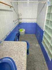 Photo of a bathroom with blue and white tiles, a granite countertop, and a washing machine.