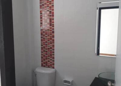 Modern bathroom with white walls and decorative red tile accent