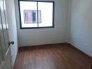 Empty bedroom with wooden floor and window