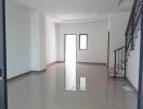 Spacious living room with shiny tiled flooring and stairs