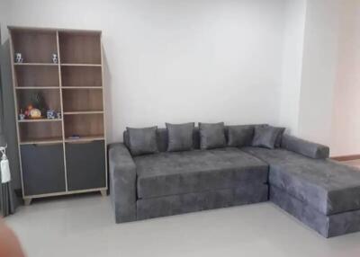 Spacious living room with modern grey sectional sofa and open shelving unit