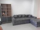 Spacious living room with modern grey sectional sofa and open shelving unit