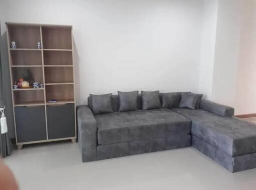 Spacious living room with modern grey sectional sofa and open shelving unit