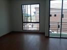 Empty living room with large windows and wooden floor