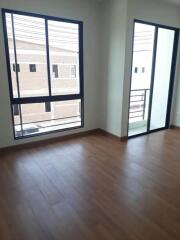 Spacious living area with wooden floor and large windows.