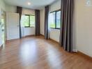 spacious bedroom with wooden flooring and large windows