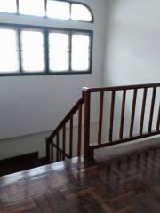 Interior staircase with wooden railing and large window